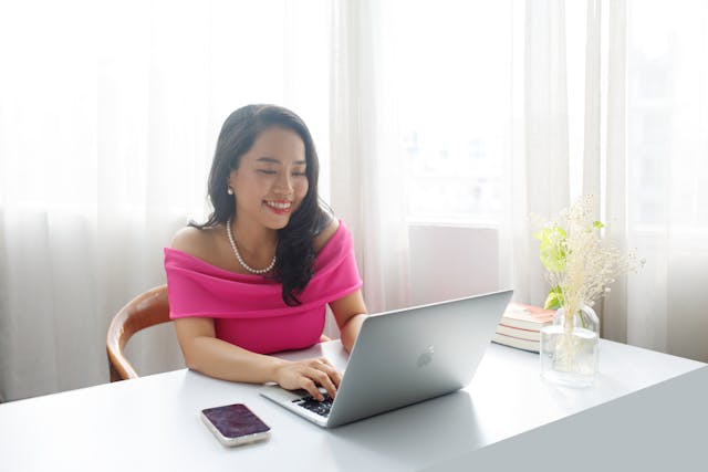 Person in a pink shirt sitting at their desk working